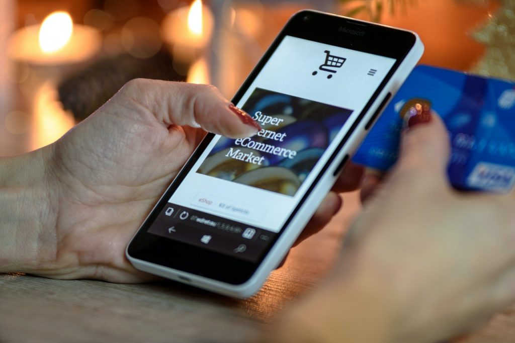 Person holding a smartphone and browsing an ecommerce store.